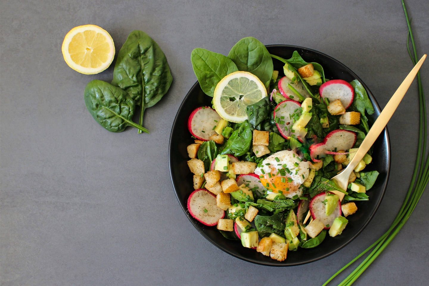 Salad bowl with spinach and herb rustikana seasoned in a black bowl with a wooden spoon
