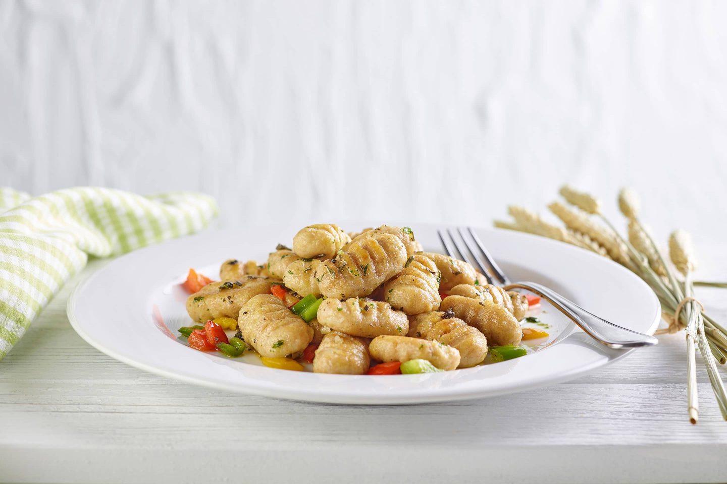 Whole grain gnocchi with fresh sage and paprika on a white plate