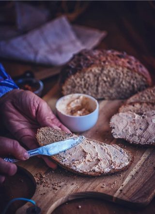 Brotstück, das mit Aufstrich bestrichen wird