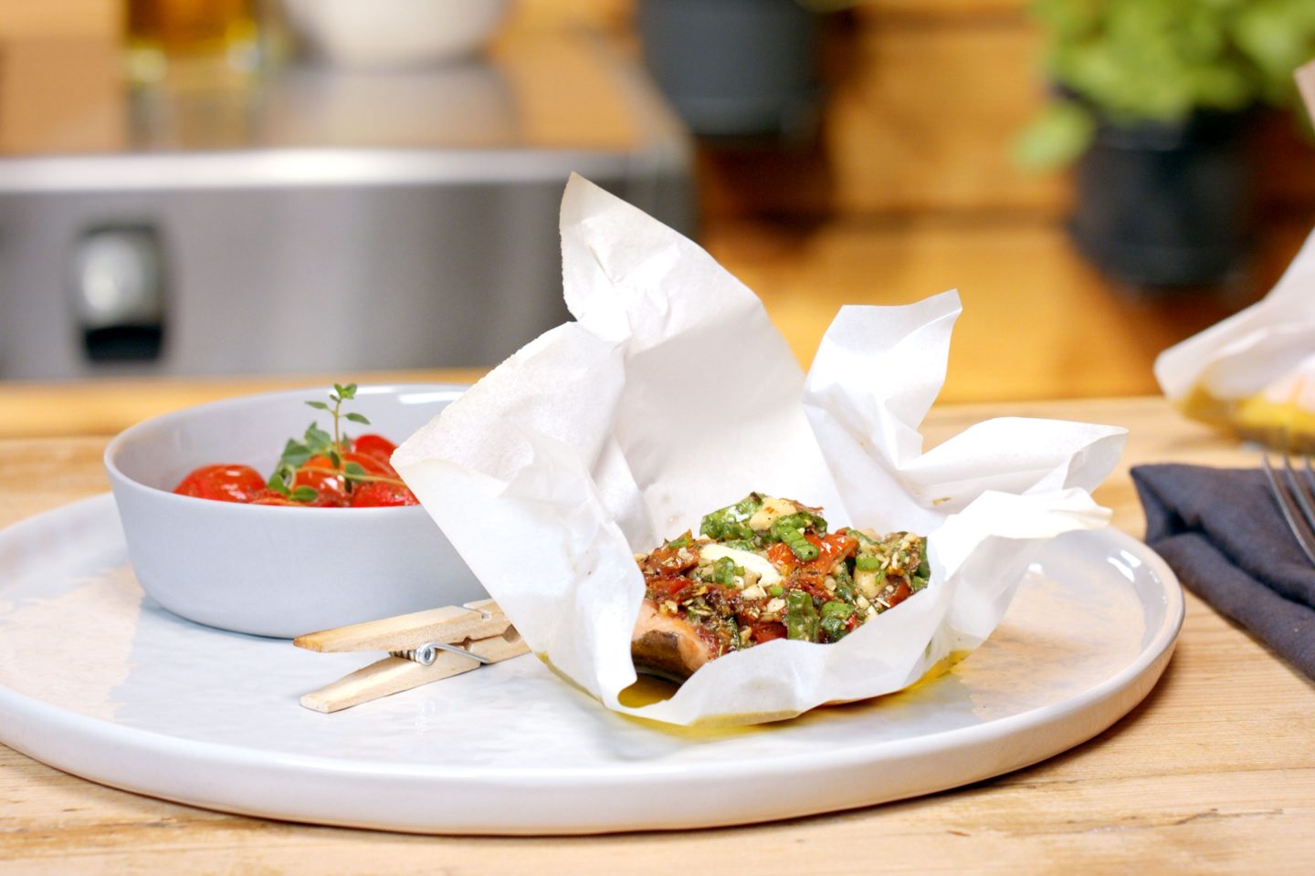 Trout in paper parcels with melting tomatoes on a grey plate