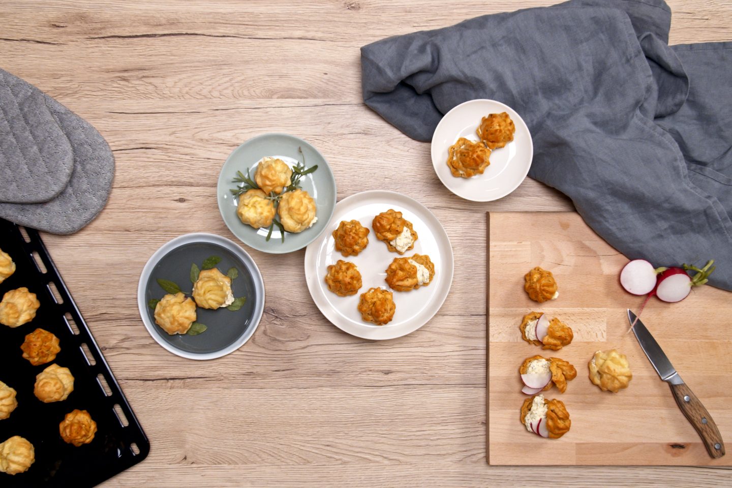 Hearty choux pastry donuts with cream cheese filling on different plates and a wooden board
