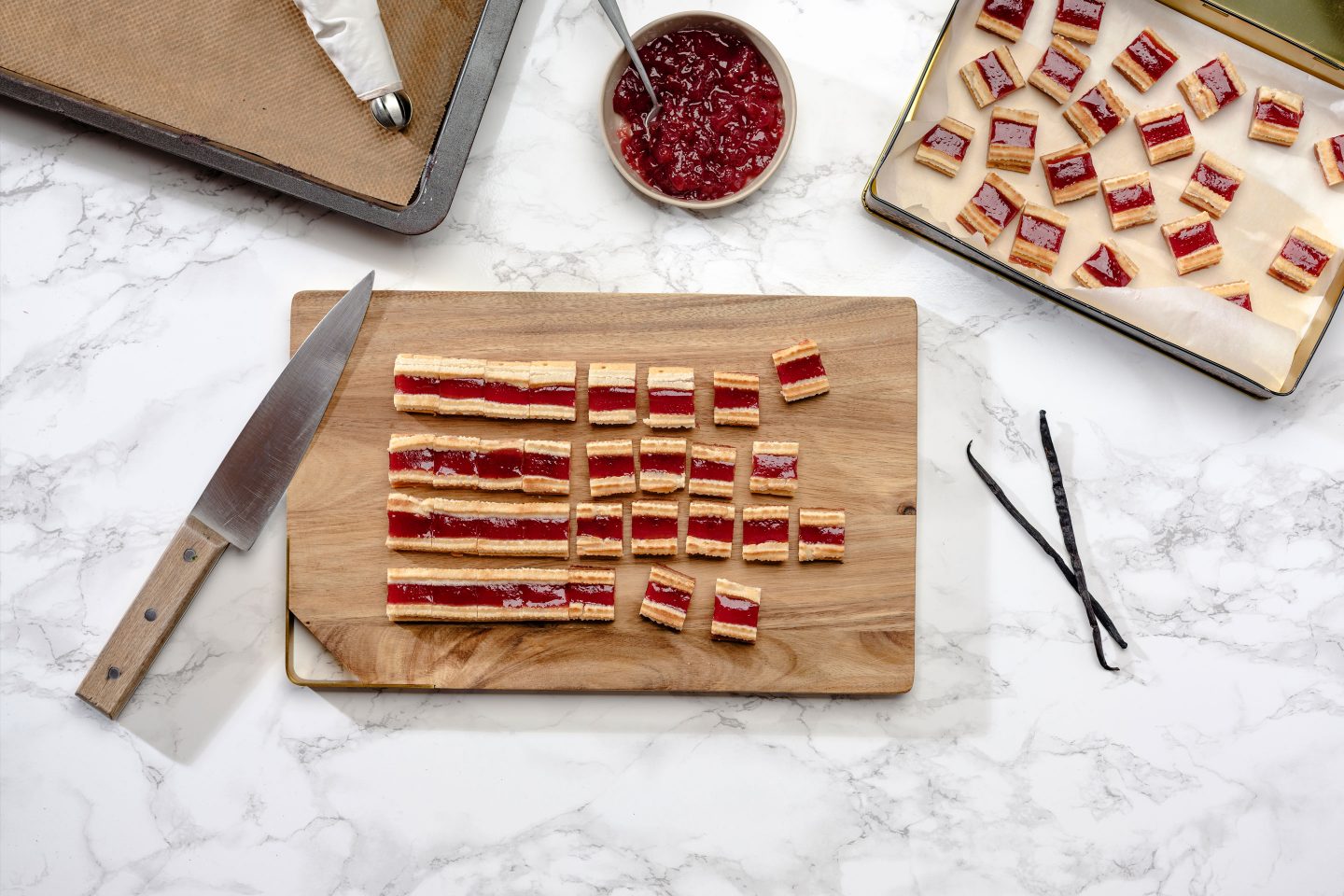 Eisenbahner cookies are being cut into ready-to-eat biscuit portions on a wooden board and layered in a golden biscuit tin