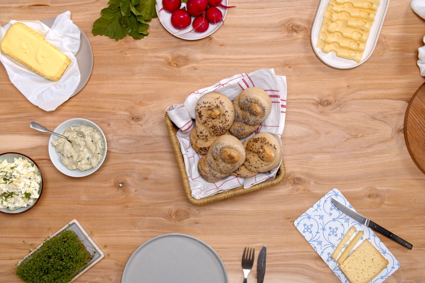 Poppy seeds in a square bread basket in the middle of a generously set table with a snack