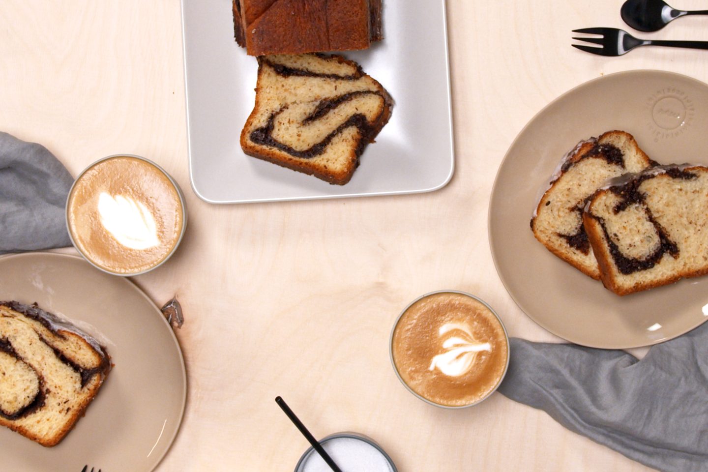 Babka with hazelnut brittle and chocolate on 2 plates with cappuccino