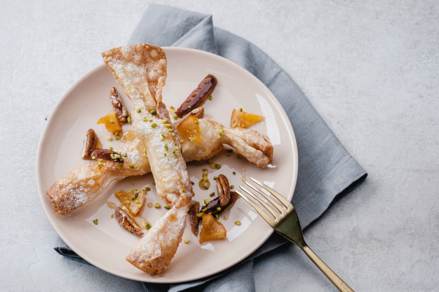Iced apple strudel pieces on a black plate with honey dates and a golden spoon