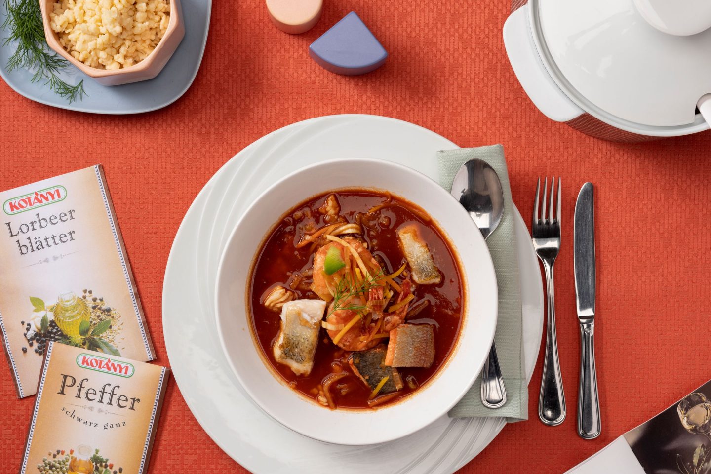 Fish and shellfish in paprika broth, beside which are sachets for bay leaves and pepper.