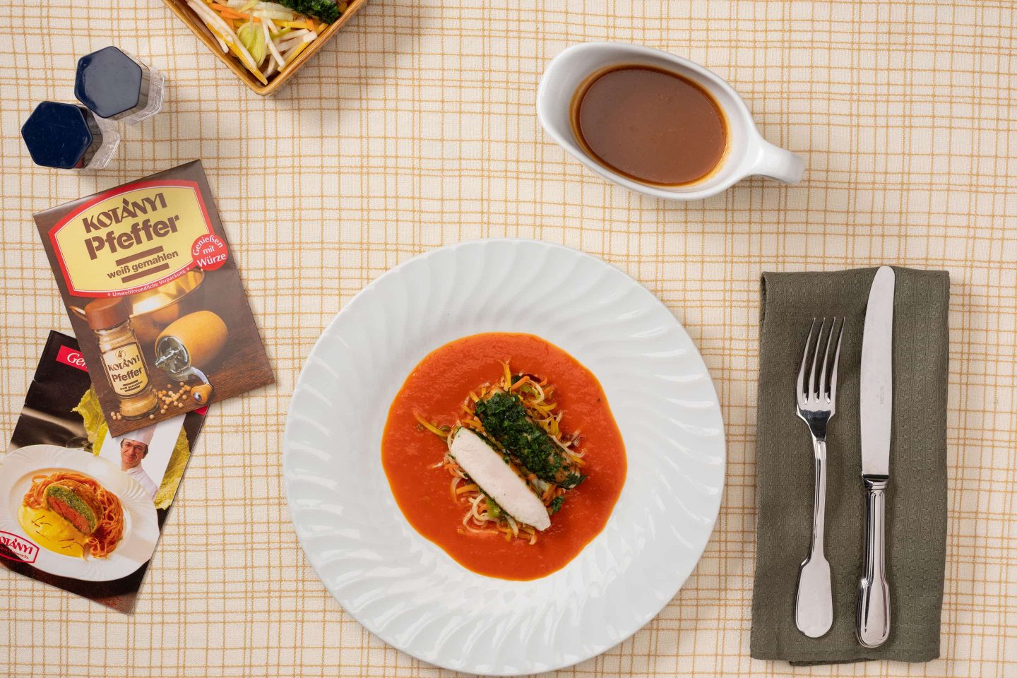 Rabbit saddle on paprika cream with vegetables, beside which is white pepper packaging.