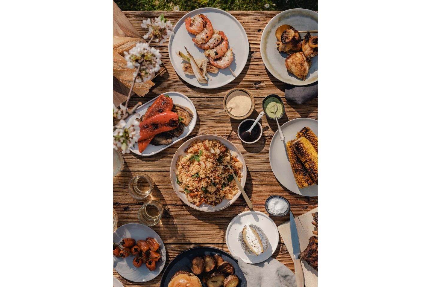 A table full of grilled dishes with bread and dips.