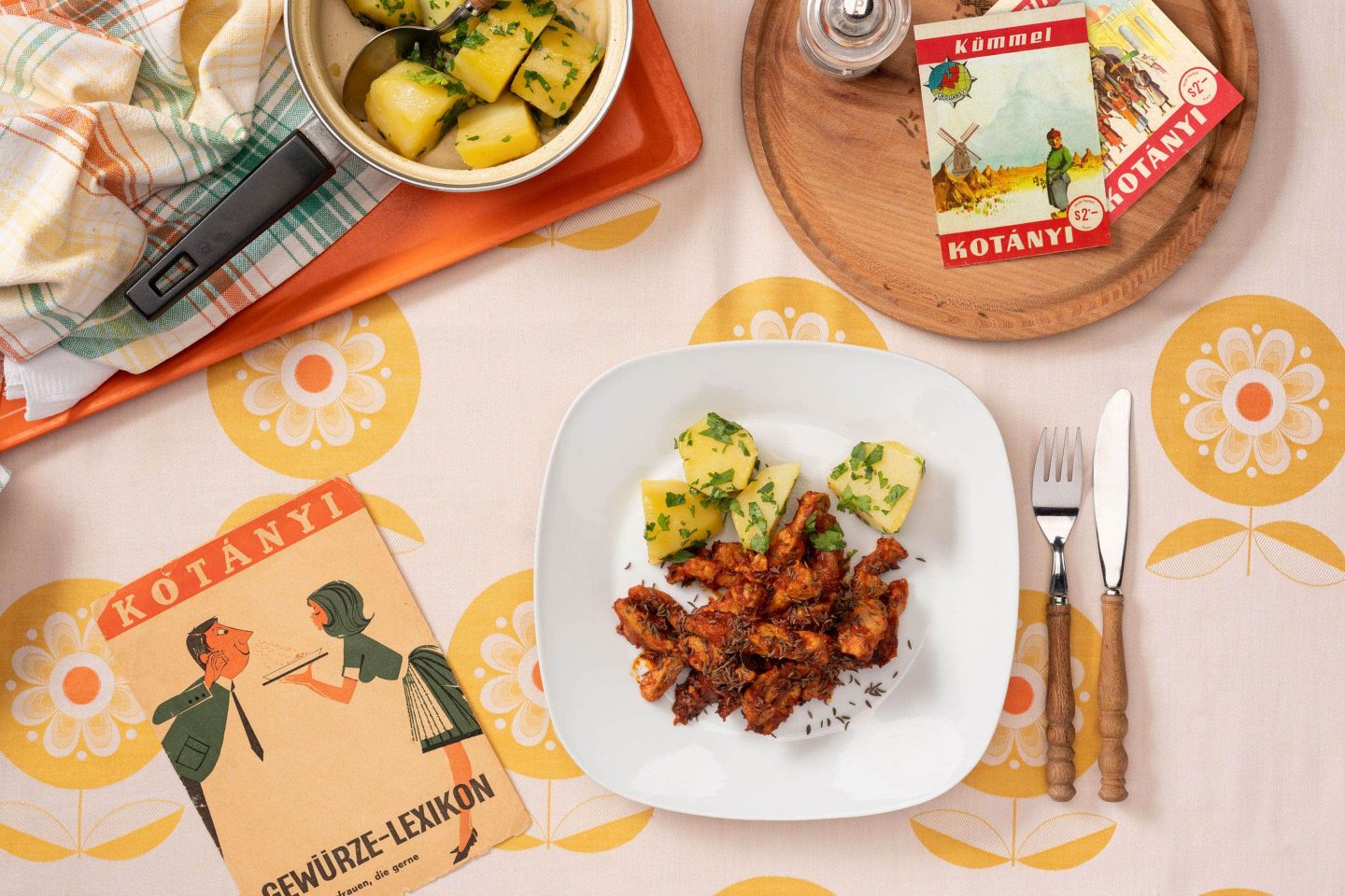 A serving of caraway-spiced pork on a slightly square plate with parsley potatoes.